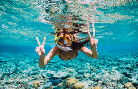 Happy young woman swimming underwater in the tropical ocean