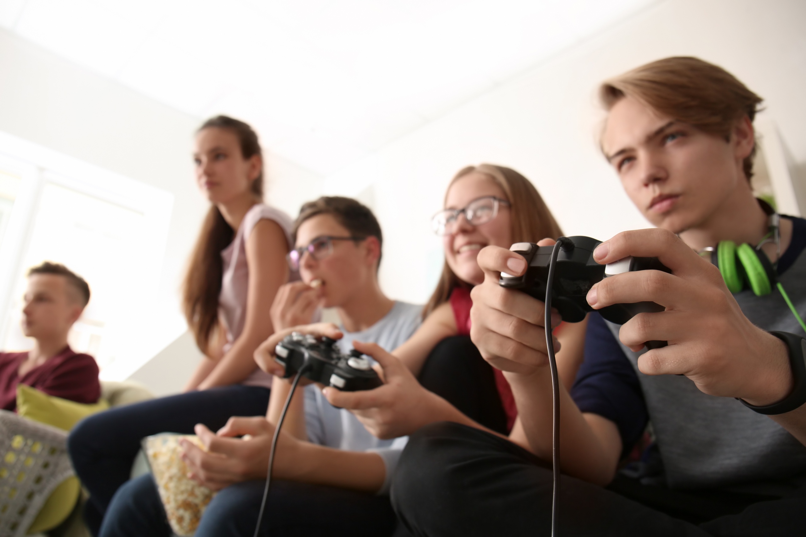 Teenagers playing video games at home