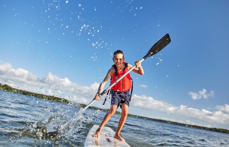 happy boy paddling on stand up paddleboard. cheerful child having fun on water. Summer vacation leisure activity